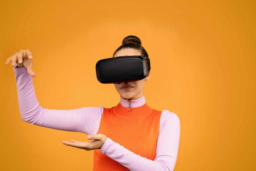 Woman in Pink and Orange Long Sleeve Shirt Wearing Black VR Goggles